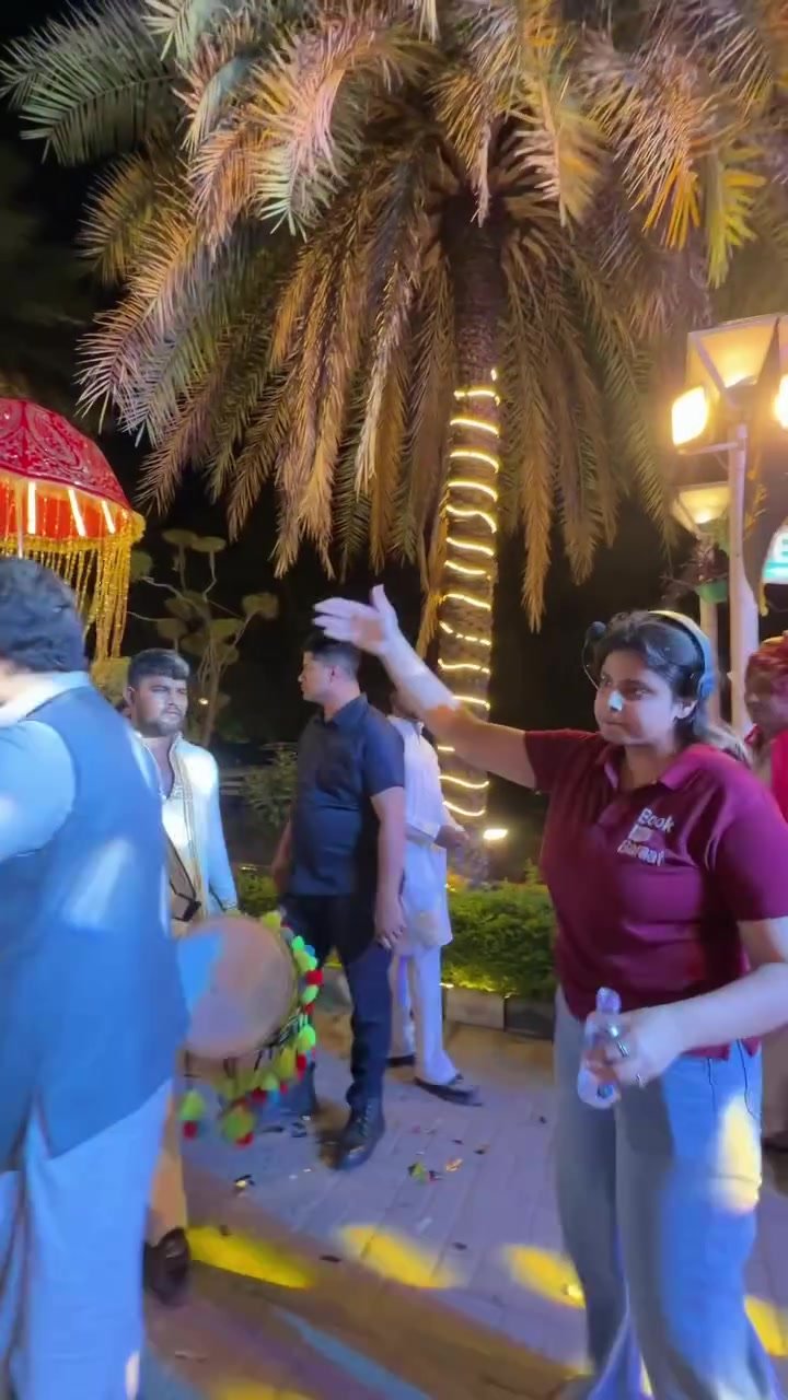 Book My Baraat coordinator gesturing beside dhol players during a night-time wedding baraat